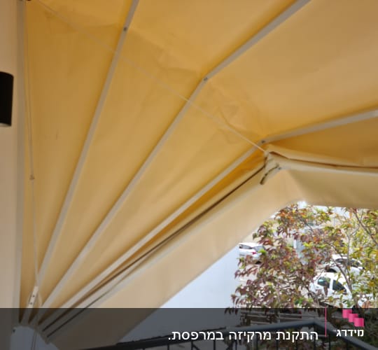 סוכך בד צהוב עם מסגרת מתכת לבנה